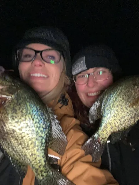 Two anglers holding crappie caught after dark on the ice