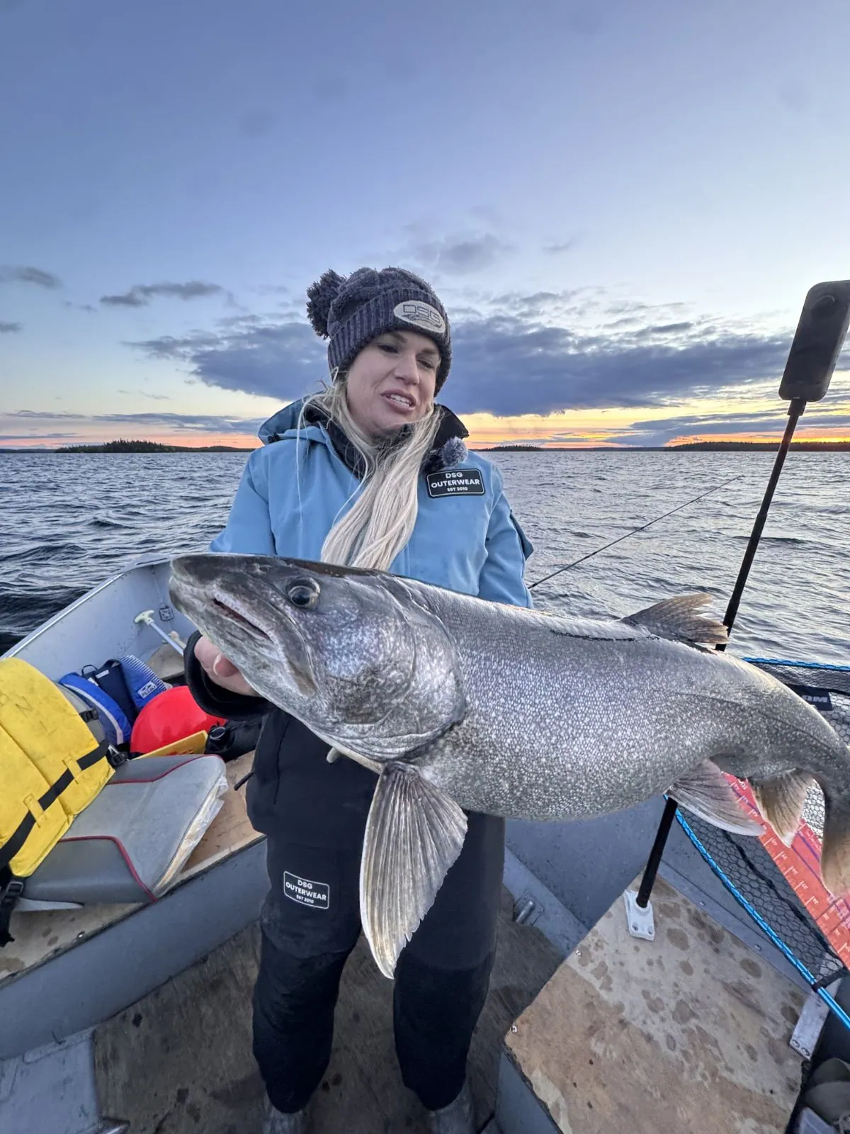 Angler holding a large lake trout at sunset on Kamuchawie Lake